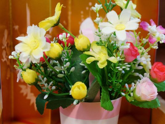 フラワーポットには、黄色いチューリップや赤いバラ、白いコスモスなど色とりどりの花に緑の葉がアレンジメントされている。