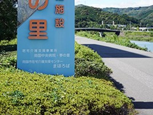 施設看板と川沿いの道  