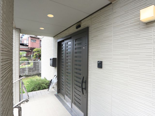 玄関扉と照明の外観 玄関 明るく清潔感のあるエントランスは、来訪者を暖かく迎え入れます。安心のセキュリティ設備も整っておりますので、ご安心ください。