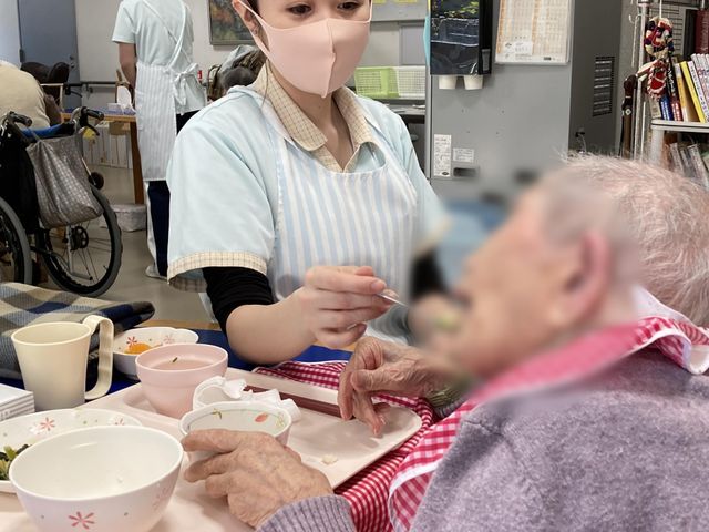 食事補助の様子 ダイニングルーム 食事を大切にサポートします。親切なスタッフが一人一人に寄り添う安心の環境です。