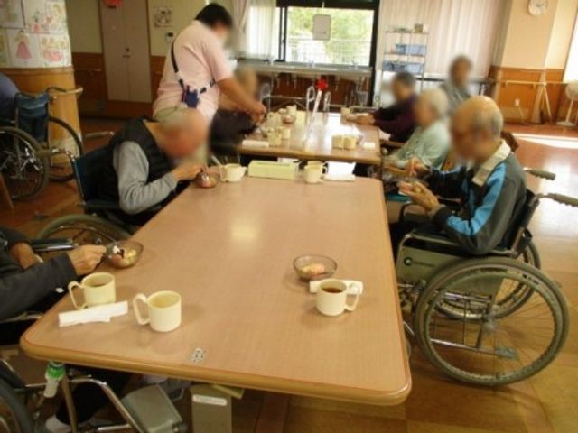 車椅子で食事を取る場面 食堂 広々とした空間で、車椅子の利用者も一緒に食事を楽しんでいます。和やかな雰囲気です。