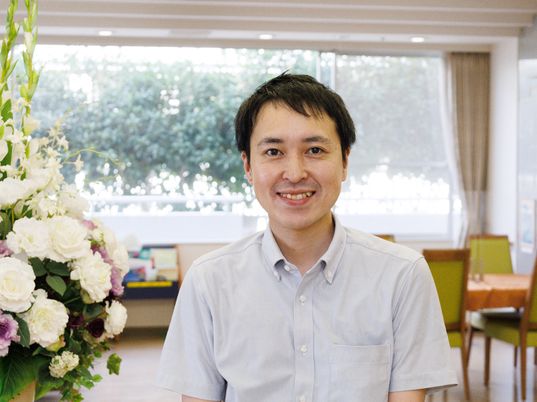 笑顔の男性と背景の食堂