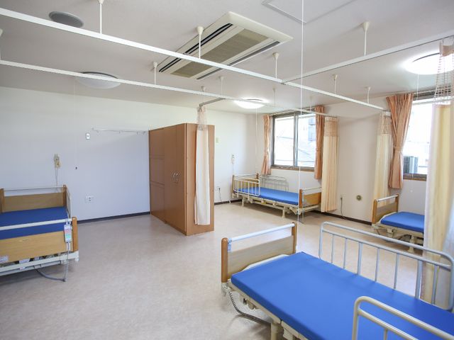 広々とした明るい居室 居室 安心の手すり付きベッドと、開放的な空間が印象的です。窓からの自然光が心地よいです。