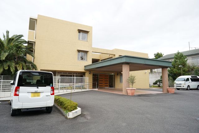 黄色い建物のエントランス 外観 明るい色合いの建物前には、広々としたスペースがあります。アクセスしやすいエントランスが迎えてくれます。