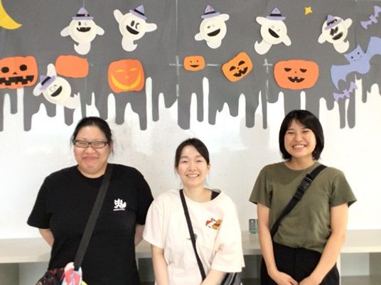 笑顔のスタッフ3人と壁飾りの休憩室  