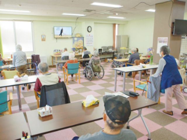 明るく広い共有スペース ラウンジ 自然光豊かなスペースで、入居者がテレビを見ながらリラックスしています。広々とした空間です。