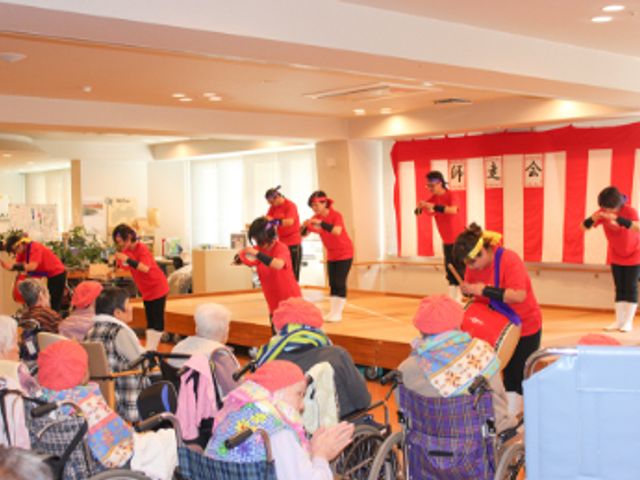演奏を楽しむ人々の様子 ラウンジ 利用者が楽器を演奏し、和やかな雰囲気の中で楽しんでいます。バリアフリーの広い空間です。