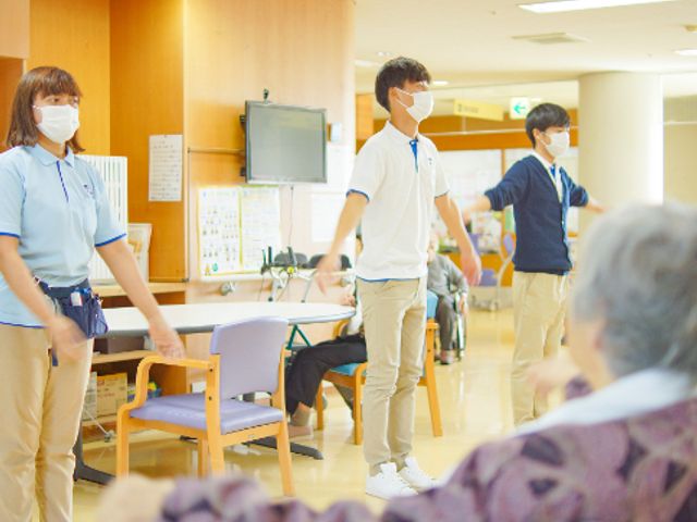 運動をする人々のいるラウンジ ラウンジ   広々としたラウンジで、スタッフと一緒にストレッチを行っています。明るく快適な空間です。