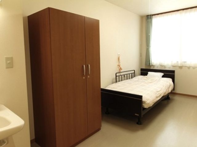 清潔な個室の居室 居室 広々とした居室は、シンプルで清潔感があり、日の光が差し込む窓が心地よい空間を作り出しています。