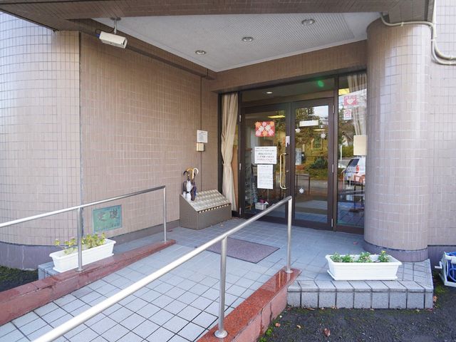 明るいエントランス 玄関 清潔感のある入口には、来訪者を迎える植木が置かれています。