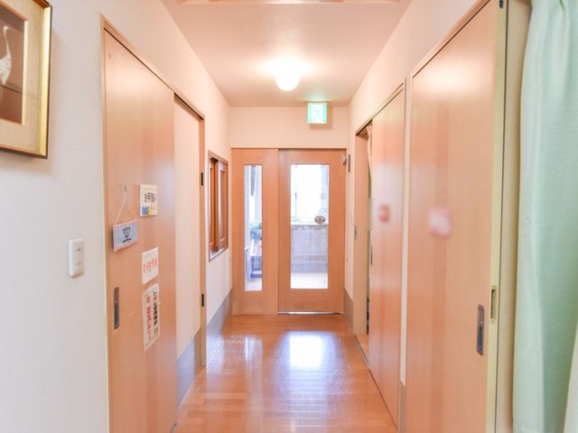 きれいな廊下の様子 廊下 ベージュの温かみある色合いの廊下は、清潔感があり通りやすい設計です。通行する人々の安全な移動を支える環境が整っています。