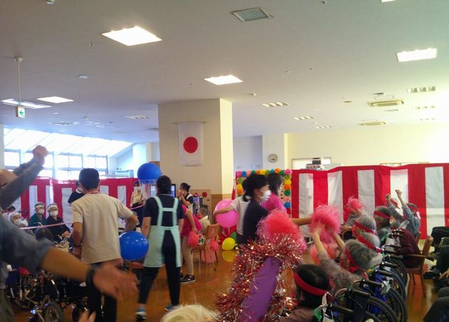 楽しいイベントの中庭 多目的室 明るく広々とした空間で、イベントを楽しむ利用者の様子が伺えます。多彩なアクティビティが豊富にあることを示唆しています。
