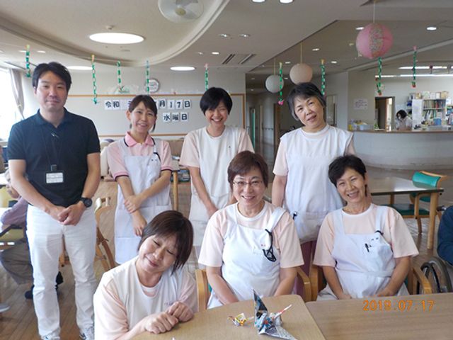 笑顔の職員たちがいる休憩室 休憩室   スタッフが笑顔で集合しています。和やかな雰囲気の中、働くことができそうです。