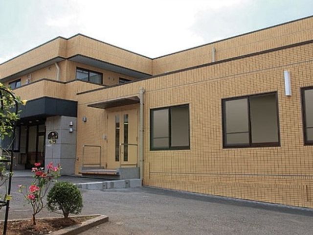 明るい外観の建物エントランス 施設外観 ゆったりとした入り口が印象的な外観です。きちんと手入れされた庭が温かい雰囲気を演出しています。