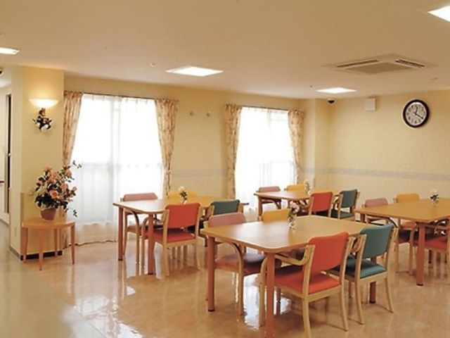 明るい食堂の一角 談話コーナー 陽光が差し込む温かみのある食堂で、利用者同士のコミュニケーションが育まれています。テーブルには生花が飾られ、明るく開放的な雰囲気です。