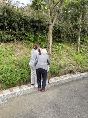見守る介助者と緑道