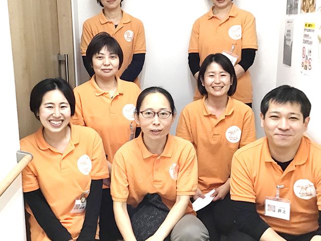 笑顔のスタッフの集合写真 スタッフイメージ 明るい雰囲気の中、協力的なスタッフたちが働いています。チームワークの良さが感じられます。