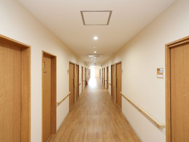 廊下の明るく清潔感ある光景 廊下 ゆとりある幅と手すりが配された廊下は、日々の安全な移動を支えます。清潔感に溢れる空間でのお仕事をご経験ください。