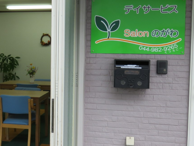 緑の看板付きエントランス エントランス 広々としたエントランスから、開放的な室内が見えます。鮮やかな緑の看板が印象的です。