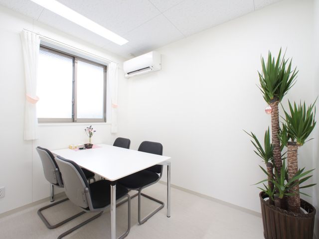 清潔な会議室 相談室 白を基調とした居室には、四人が使用できるテーブルと植物が配置され、落ち着いた雰囲気で対話が楽しめます。