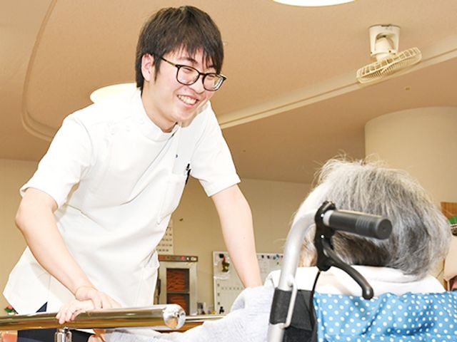 笑顔で話す男性スタッフの室内 スタッフイメージ 笑顔のスタッフが親身に対応し、安心して過ごせる雰囲気が伝わります。