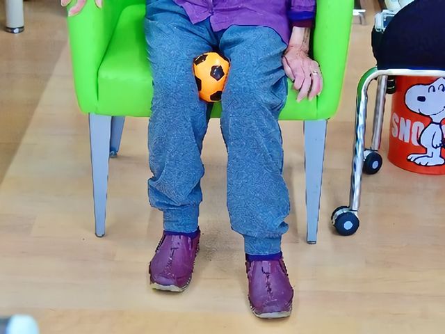 楽しい時を過ごす様子 多目的室 明るい色の椅子に座る方が球体を手にして、優しい環境で過ごされています。安らぎの空間でのひとときをご提供します。