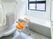 オレンジのシャワーチェアやシャワーが設置された浴室には、一人用の浴槽が設置され、手すりも付いている。