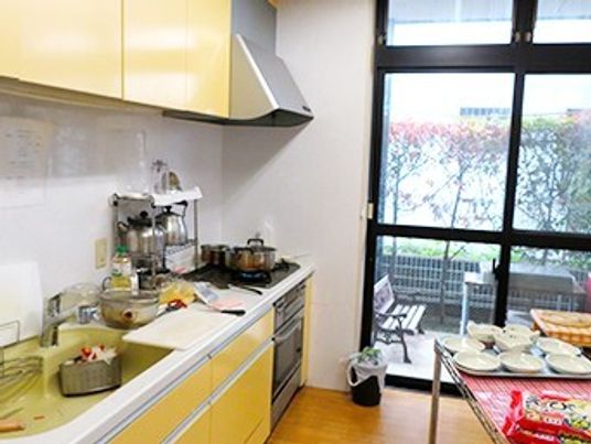 IHクッキングヒーター付きのキッチン。収納の扉は黄色で明るい雰囲気。テーブルの上には複数の皿が並べられたトレーがある。