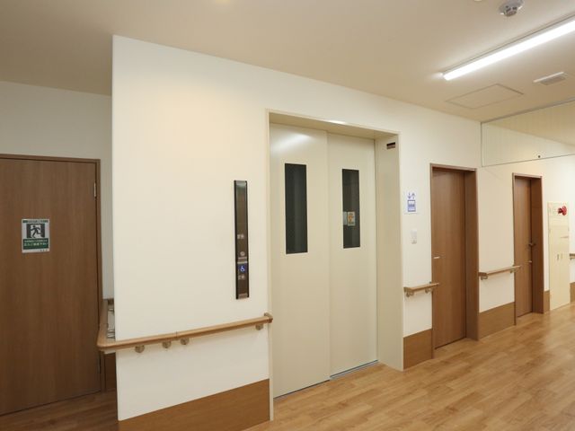 廊下と複数の出入口 エレベーター 手すりが設けられた清潔感のあふれる廊下です。出入口には障がいがある方も考慮した設計が施され、安全性に配慮されています。