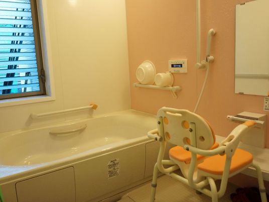 浴槽に加え、シャワーも設置されているタイプの浴室。シャワー部分に鏡が付いており、その前に入浴用の椅子が置かれている。