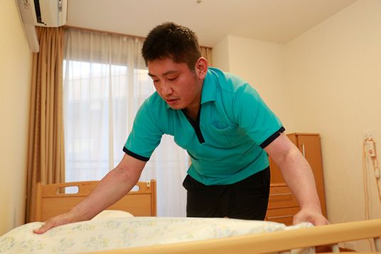 ベッドメイキングをする人の居室