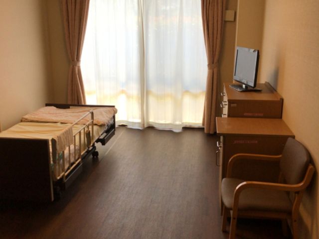 落ち着いた居室 居室 広々とした居室は、ベッドと椅子が配置され、ゆったりと過ごせます。自然光が差し込む明るい空間です。
