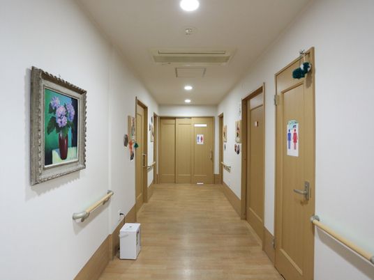 廊下は落ち着いた木目調の床で、部屋の出入口のドアーのとも調和している。壁は白く、絵画が飾られている。