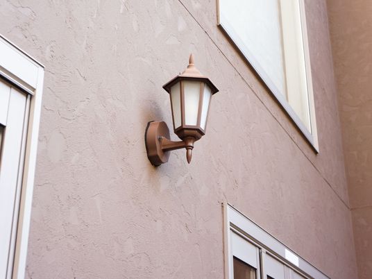 建物の壁はおしゃれな塗り壁で、薄い茶色をしている。窓がいくつか付いており、その一角にランプ状の照明が取り付けられている。