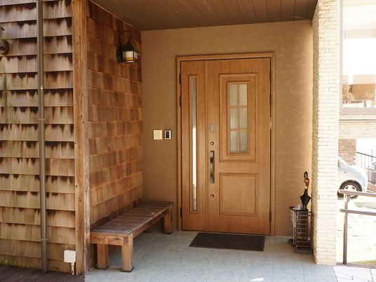 施設の玄関は、木製の板が組まれていてランプ型の照明が付いている。ベンチも置かれている。玄関の扉も木製である。