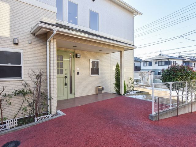 明るいエントランス外観 外観 バリアフリー設計のエントランスは、来訪者を温かく迎える配色となっており、スタッフが笑顔で出迎えてくれる様子が想像できます。
