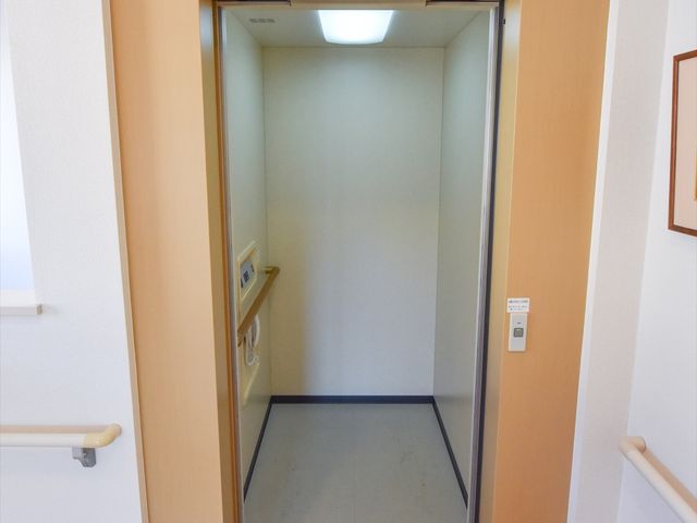 明るい廊下のエレベーター エレベーター 手すり付きで安全な移動を支援するエレベーターです。設備が整った環境で快適に勤務していただけます。