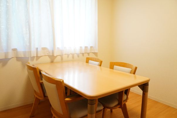 窓から光が差し込み、テーブル、椅子が置かれている共有スペース