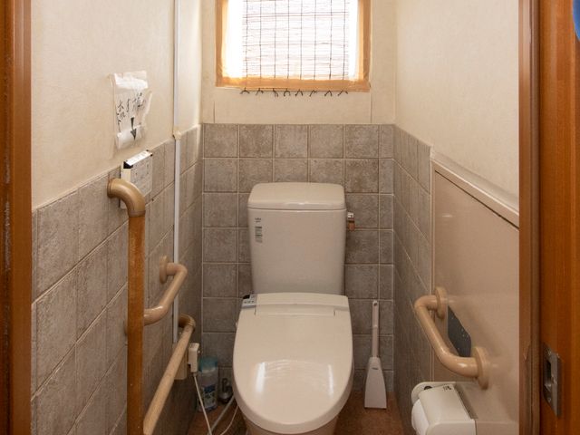 手すり付きトイレ トイレ 手すりが取り付けられた明るいトイレで、利用者の安全を考慮した設計です。