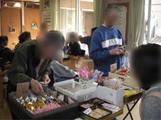 施設の写真 共有スペースでは、駄菓子屋が開かれ、入居者様がお買い物されている様子である。子供の頃の懐かいイベントもご用意している。