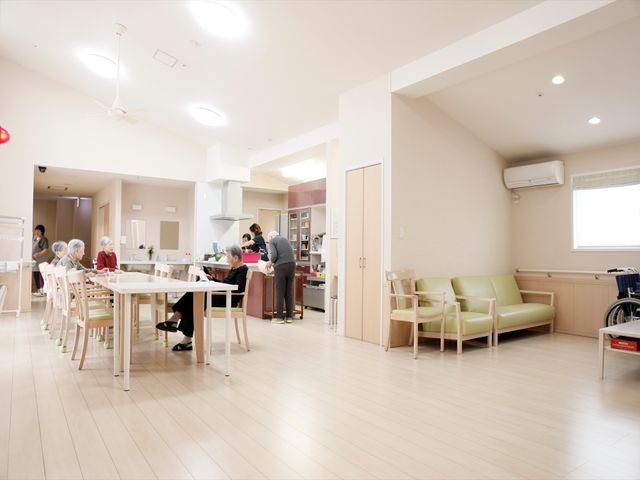 明るい共有ダイニング空間 リビング 広々としたダイニングでは、利用者がお食事や交流を楽しんでいます。心地よい光が差し込むこの空間で、美味しい料理と共に心温まる時間を過ごすことができます。