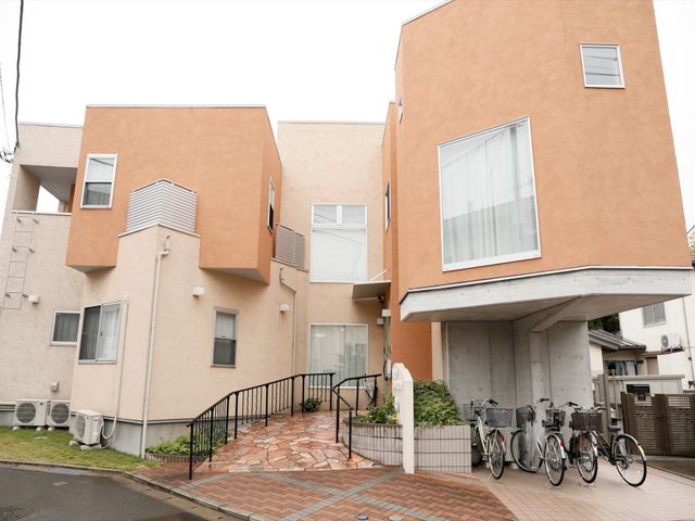 温かみのあるオレンジ色の外観 外観 オレンジ色を基調とした温かい印象の建物です。自転車が並ぶエントランスが、来訪者をやさしく迎え入れます。