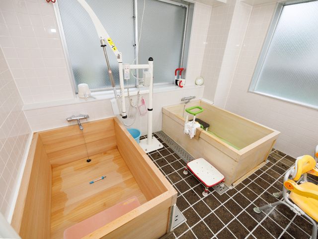 木製の広々とした浴室 浴室 床には滑りにくいタイルが使用され、安心してご使用いただける木製のバスタブが配置されています。サポート用の椅子も備え、入浴時の安全を考慮した設計です。