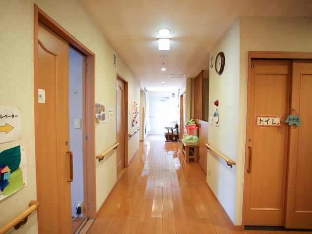 清潔な廊下の様子 廊下 手すりが設置された温かみのある廊下です。清潔感があり、安心して業務に取り組むことができそうです。