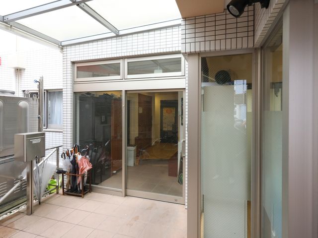 エントランスの透明な扉 エントランス 開放的なエントランスは、透明な扉を通して明るく、来訪者を暖かく迎え入れます。傘立てがあり、来訪者の小さなニーズも配慮されています。