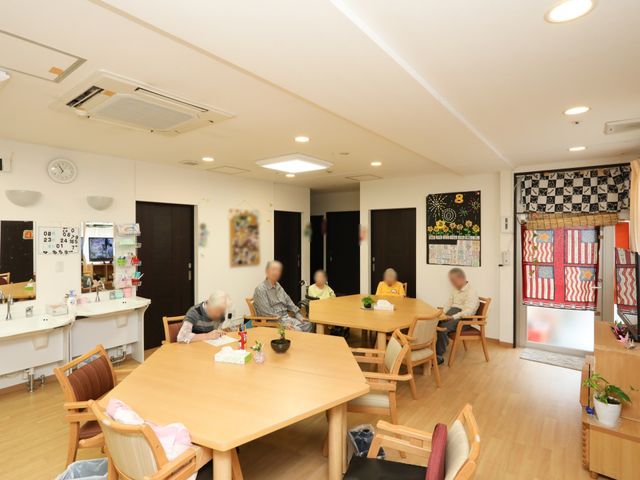 共有スペースでの憩いの時間 共有スペース 明るく広々とした食堂で、利用者同士が穏やかに交流を楽しんでいます。時計やカレンダーも備えられ、日常生活に寄り添った設計です。