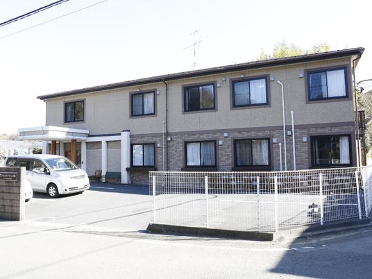 自然豊かな立地に建っている。鉄骨造2階建の家庭的な雰囲気の施設である。前には駐車スペースが確保されている。