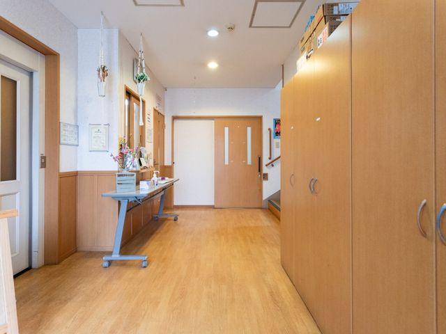 明るい廊下 廊下 温かみのある木目調の明るい廊下です。物品や装飾が整然と並べられています。