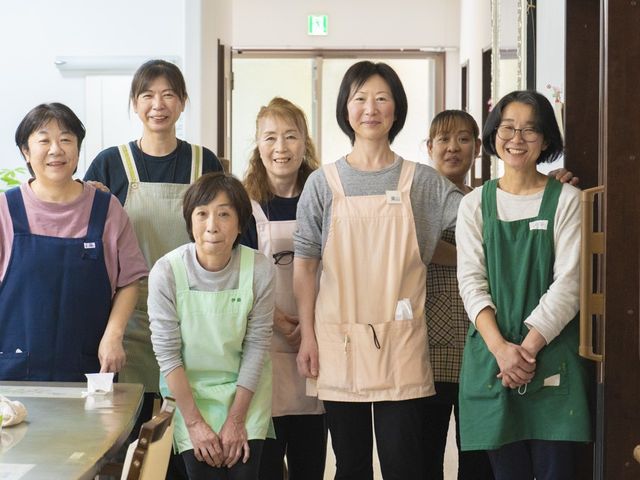 笑顔のスタッフが並ぶ食堂 食堂   明るい食堂で、スタッフの皆さんが笑顔で並んでいます。就業時の雰囲気が伝わりやすく、あたたかい職場を感じられます。