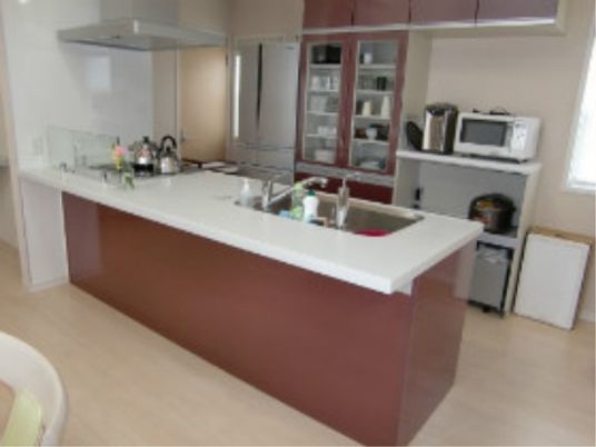 白とダークブラウンのキッチンスペースは、モダンでお洒落な空間である。対面式で壁際に食器棚を設定している。